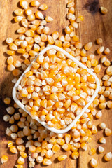 Popcorn kernels in bowl on wooden surface