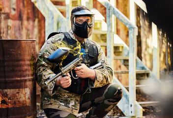 Fototapeta premium Paintball, portrait or male soldier with gun in shooting game playing on fun training battlefield mission. Man or focused warrior with army weapons gear for survival in military challenge competition