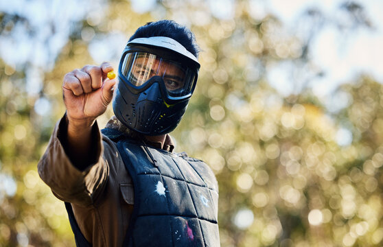 Man, paintball and hands holding ball on the battlefield for war, shot or engaging act in nature. Male paintballer or soldier showing or pinching paint bullet in military or extreme adrenaline sports