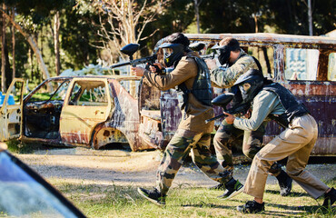 Team, paintball and army moving on the attack in extreme adrenaline sport, battle or war in the nature outdoors. Group of people soldiers walking or aiming down sights in teamwork sports engagement