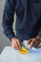 Young businessman searching piles of documents on desk for financial report paper revenue data statistics Business expenditures to prepare records on laptop with reports and clarifications.