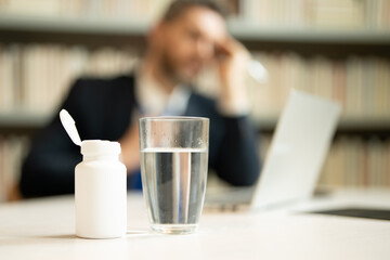 Headache, tiredness and stress. Man in suit uses a laptop, is tired got headache migraine. Headache pain concept. Painful men are stressed at work in office. Stressful and headache.