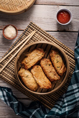 dim sum dumplings in bamboo steamer with sauce on wood table. top view