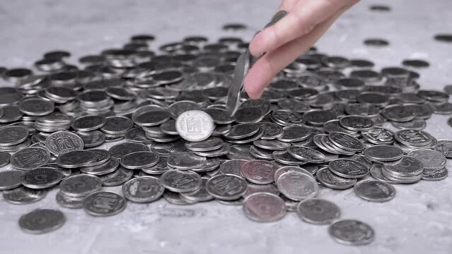 Handful of Coins Fall from Hands into a Pile of Scattered Kopecks on the Table. A scattering of Ukrainian silver five-kopeck coins. Cash flow. The financial crisis, budget savings, money accumulation.