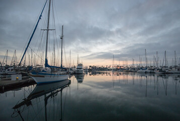 Fototapeta na wymiar Boat and sunrise sky reflections in the Channel Islands harbor at Port Hueneme on the gold coast of California United States