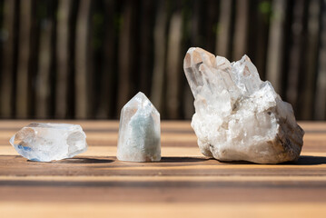 Three white quartz crystals on a table - obrazy, fototapety, plakaty