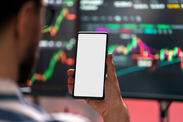 Crypto trader holding smartphone using mobile app looking at mobile screen with mockup, selective focus. Online trading concept 