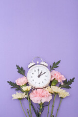 Reloj despertador color blanco ilustrando cambio de horario primavera, verano con base de flores...