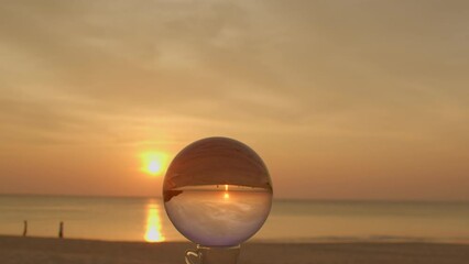 .The natural view of the sea and sky in beautiful sunset are unconventional and beautiful inside crystal ball. .A image for a unique and creative travel. 4K Videos for beautiful and unusual 
