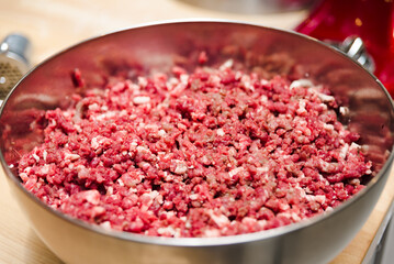 minced meat in a deep steel bowl on a wooden table close up
