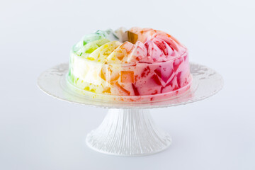 A fruit flavoured, rainbow coloured jelly mold on a pedestal stand.
