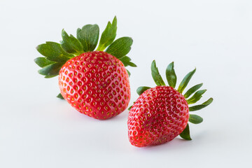 Two isolated fresh strawberries against a white background.