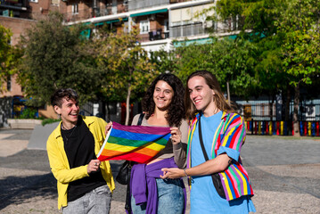 Young diverse friends walking on the street with the lgbt rainbow flag.