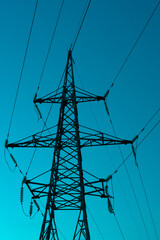 High voltage electric tower silhouette on bright blue background.