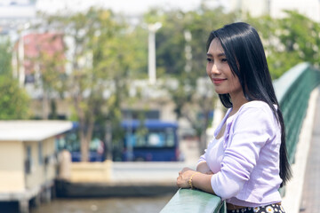 A young woman looks from the bridge over the Chao Phraya river in the center of Bangkok, Thailand