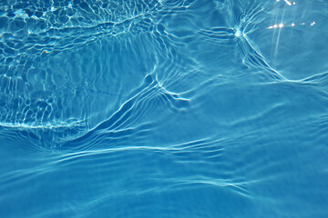 Defocus blurred transparent blue colored clear calm water surface texture with splashes and bubbles. Trendy abstract nature background. Water waves in sunlight with copy space. Blue water shine