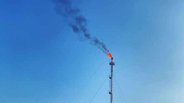 Burning torch Gas flare refinery against clear blue sky, minimal background