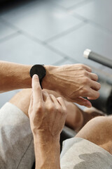 Naklejka premium Hands of sporstman checking smart watch to track his activity