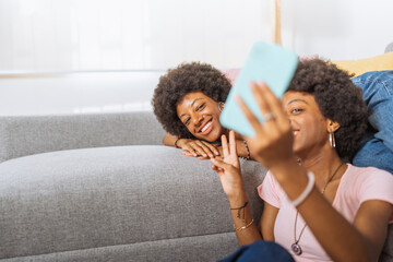 Twin sisters, taking a selfie with their cell phone, in the living room