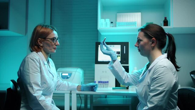 Veteinary doctors in a laboratory mixing a red blood sample in a test tube. They are in a laboratory and look serious. They are very focused. High quality 4k footage 
