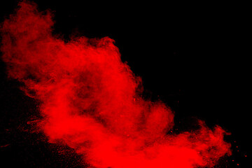 Red powder explosion cloud on black background. Freeze motion of red color dust  particles splashing.