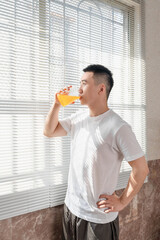 Fototapeta premium Asian man is drinking juice near the window in the morning.