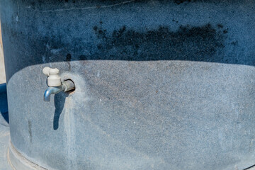 Closeup of water tap in side of cement water fountain.