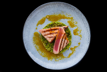 Beefsteak medium rare with blood served with peas isolated on black background side view