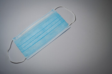 Blue surgical mask with rubber ears straps on gray background, Bacteria protection concept.