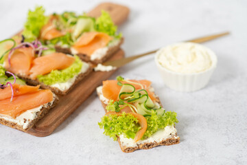 Homemade Crispbread toast with Smoked Salmon, Melted Cheese and cress salad. on white wooden board.