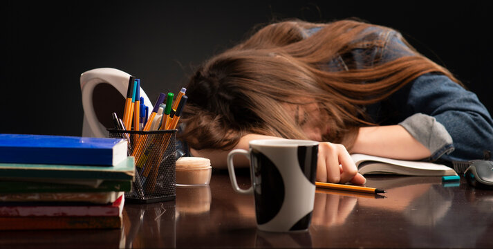 Female student sleeping with books at her desk.