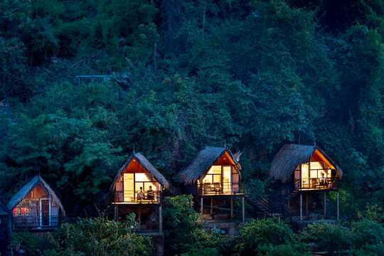 Three small wooden houses with lights in the tropical forest