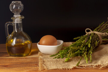 bunch of wild asparagus with a jar of olive oil and eggs