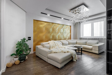 Living room with white walls and a huge white sofa, a black glossy wardrobe with a large yellow 3D panel on the wall