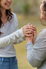 Close up of Adult daughter holding her elderly mother hand with love and walk together - obrazy, fototapety, plakaty