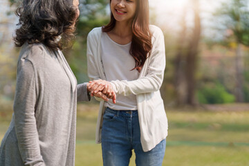 Close up of Adult daughter holding her elderly mother hand with love and walk together