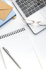 Modern white office desk table with laptop, notebook and other supplies.