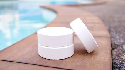 Tablet chlorine for swimming pool, white round chlorine on swimming pool background, chemical pool...