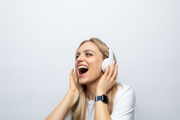 Fototapeta premium young woman sing along to music from headphones among white background