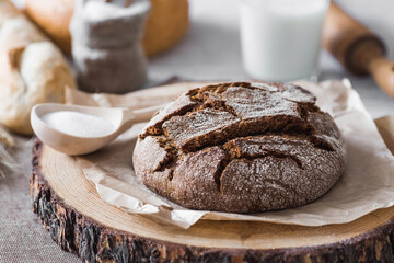 Fresh delicious bread close-up and salt. Freshly baked sourdough bread with a golden crust on a wooden board. The context of a bakery with delicious bread. Confectionery products.