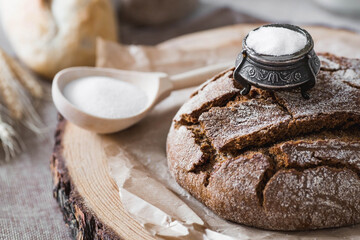 Fresh delicious bread close-up and salt. Freshly baked sourdough bread with a golden crust on a wooden board. The context of a bakery with delicious bread. Confectionery products.