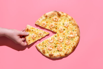 Shrimp pizza isolated on a pink background. Woman taking a slice of pizza