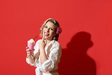 Woman drinking a milkshake against a red background. Retro style woman portrait