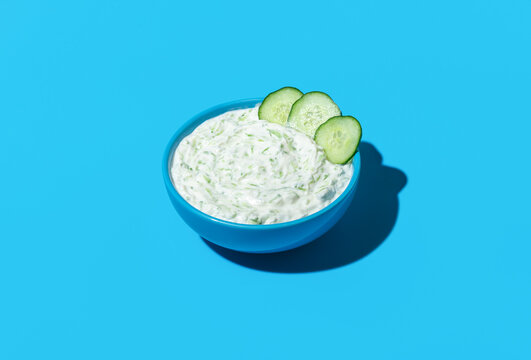 Bowl with tzatziki sauce isolated on a blue background