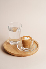 Coffee art latte and glass of water on wooden tray