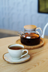 Cup tea and glass teapot on wooden table