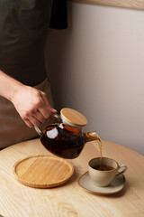 Hand pouring tea from teapot in cup