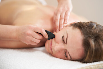 Fototapeta na wymiar Woman having a gua sha massage in salon