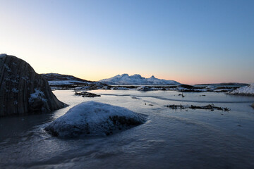 Wide angle landscape shot of the snow covered mountains and beach near Mjelle, part of the Bodo...