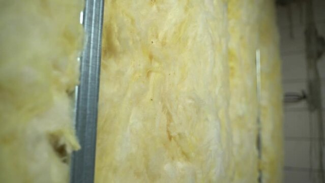 Yellow glass wool in the wall in a private house close-up, smooth camera sliding